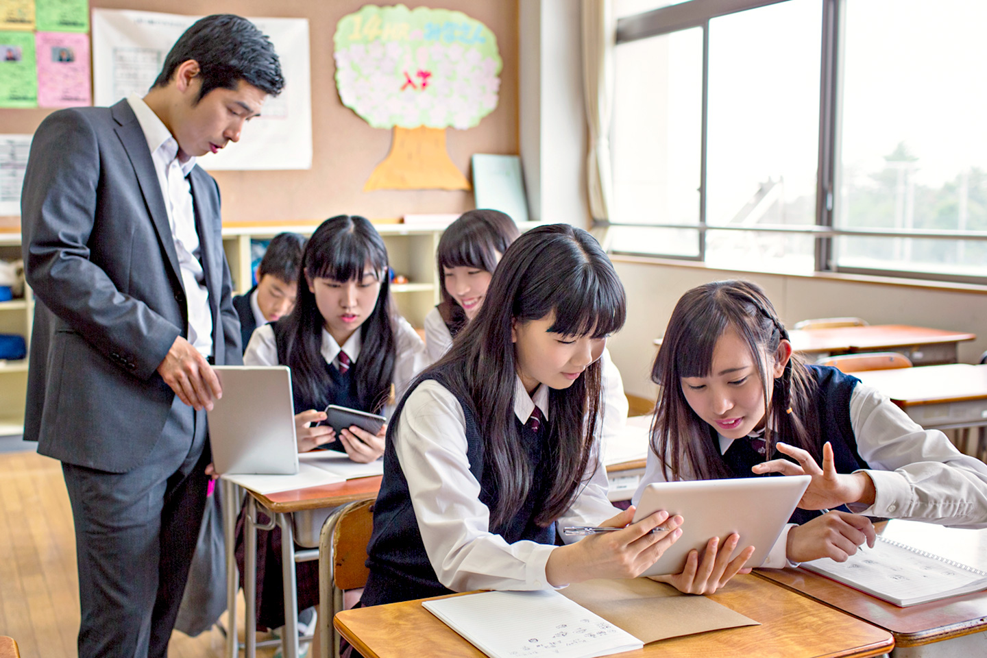 教員と生徒が授業でタブレット端末を操作している様子